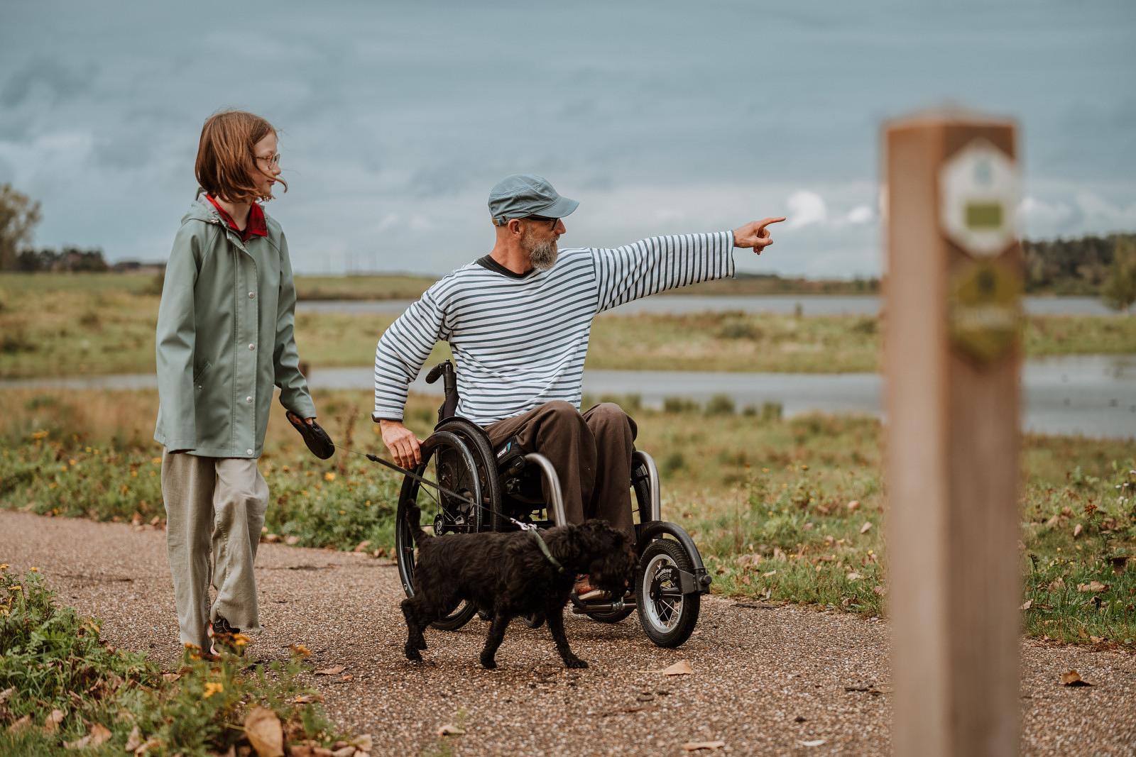 Rolstoelgebruiker met kind en hond langs de Maas © Visual Nomad