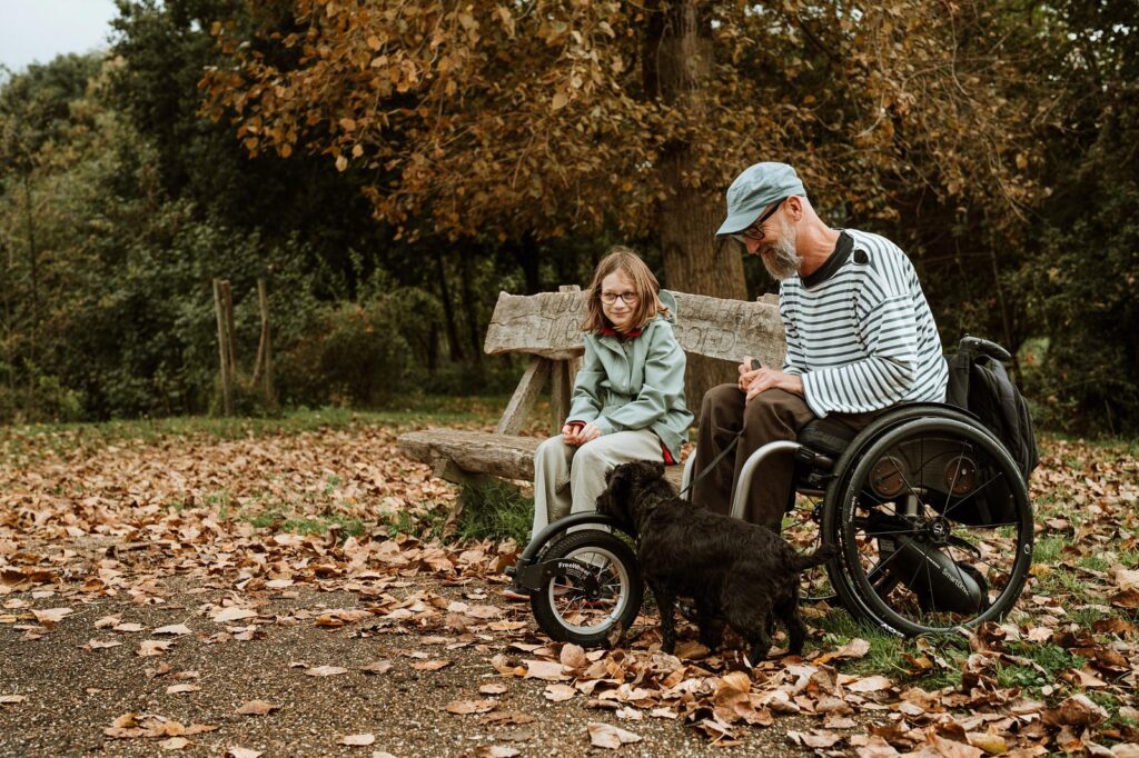 vader in rolstoel met dochter en hond op bankje in Negenoord © Visual Nomad